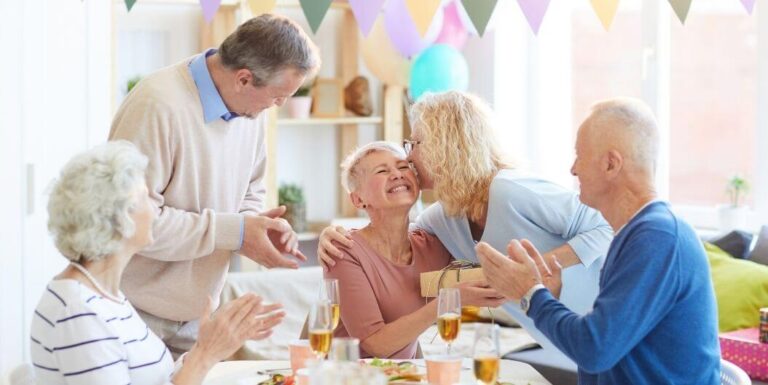 Elderly Friends Celebrating Birthday with Gifts at Independent Living Facility